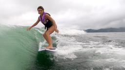 a young lady wakesurfs on lake arenal