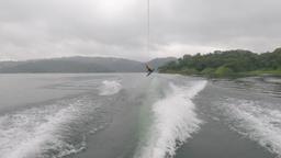 a man wakeboards jumping in the air above lake arenal on a foggy morning