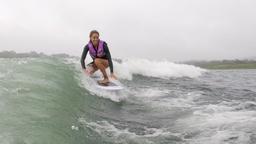 a smiling lady wakesurfs on lake arenal trying to keep balance