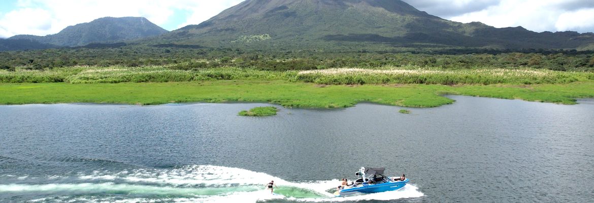 a wakesurfer follows the wake with a view of arenal volcano