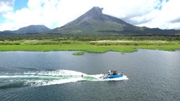 a wakesurfer follows the wake with a view of arenal volcano
