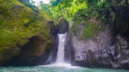 man standing on balanced rock of pavon waterfall tour manuel antonio