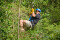        Man Zooming Across A Rainforest Field On Blue River Zipline
  - Costa Rica