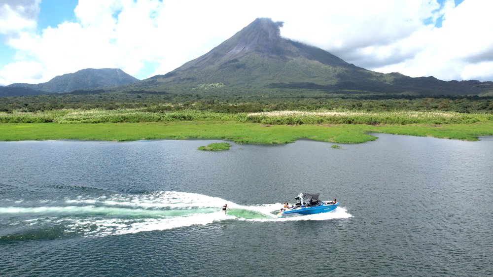 a wakesurfer follows the wake with a view of arenal volcano
 - Costa Rica