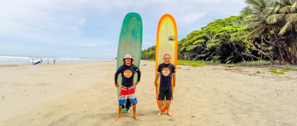 olingo tours surf lesson students holding board
 - Costa Rica